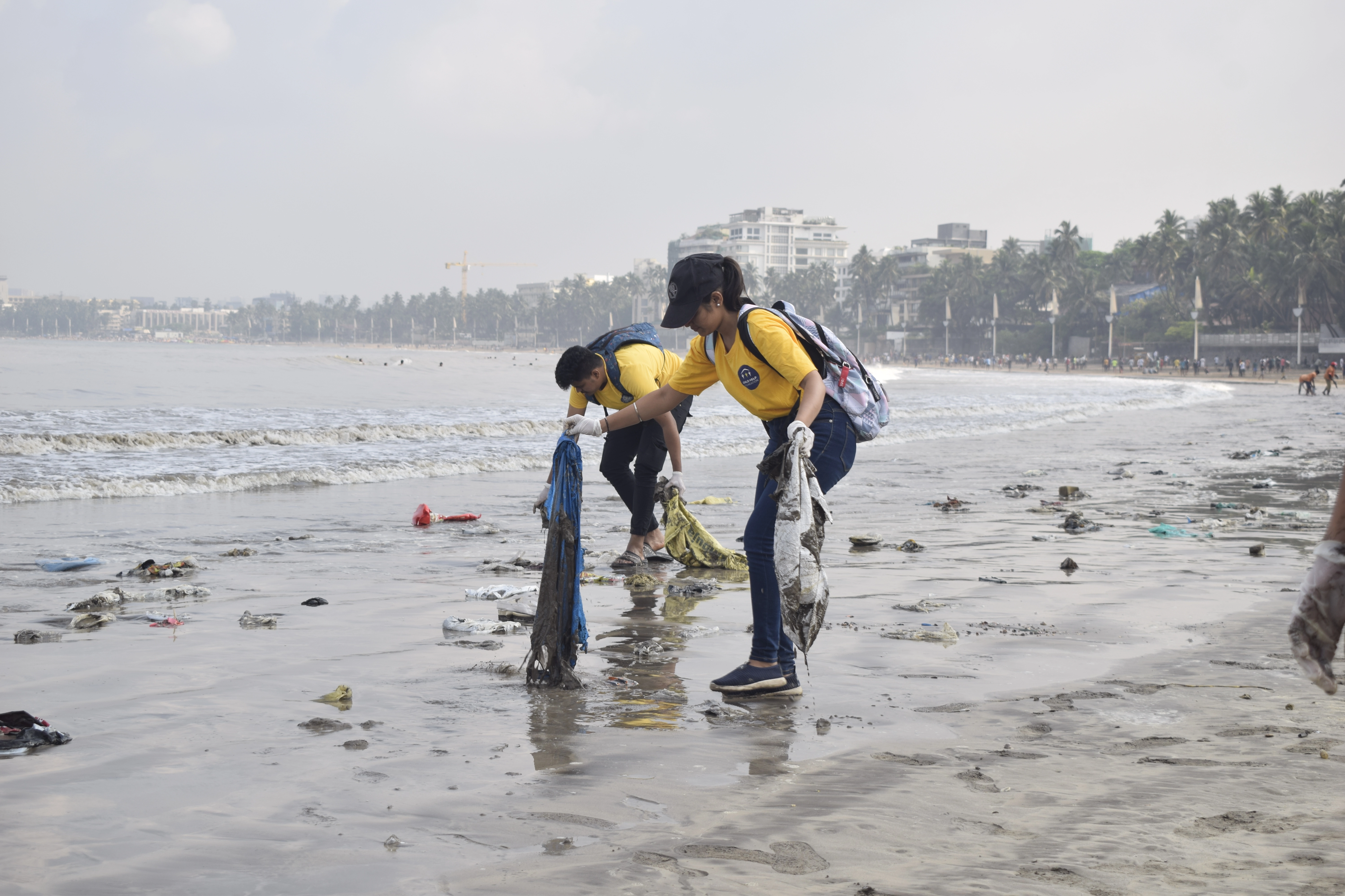 Child Help Foundation volunteers in yellow T-shirts collecting plastic waste on Juhu beach